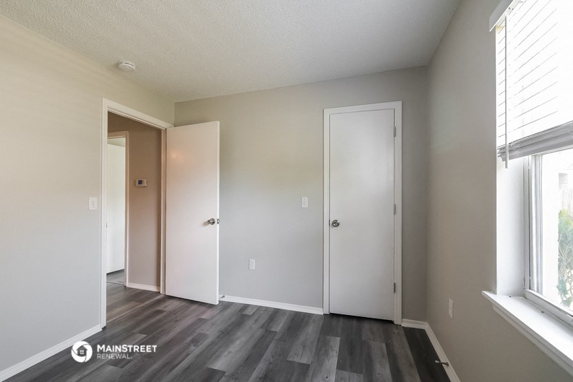 the living room of an apartment with wood floors and white walls
