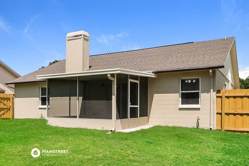 a view of the front of a tan house with a wood fence