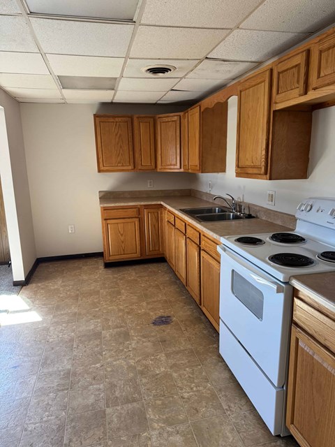 A kitchen with a white stove top oven and wooden cabinets.