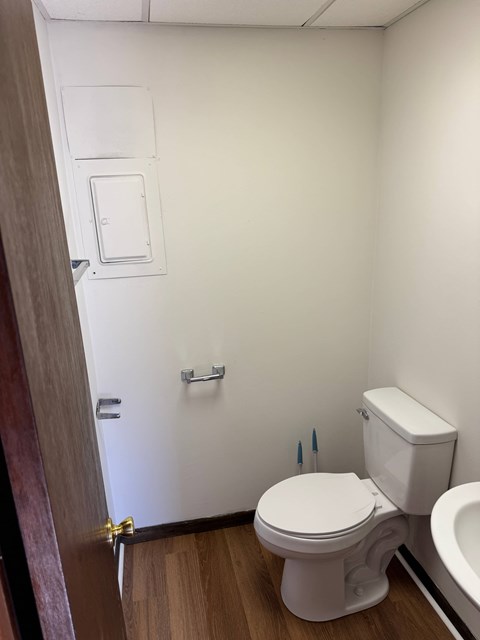 A white toilet sits in a bathroom next to a white sink.