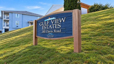 A sign for Gulf View Estates stands in front of a grassy hill.