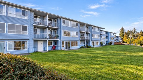A row of apartment buildings with green lawns in front.