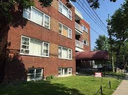 a red brick apartment building with a green yard