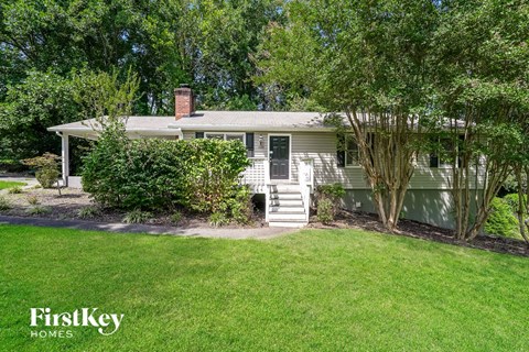 A house with a front yard and a tree in the front.
