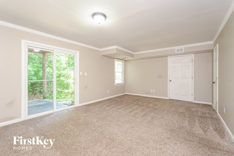 A spacious room with a carpeted floor and a sliding glass door leading to a garden.