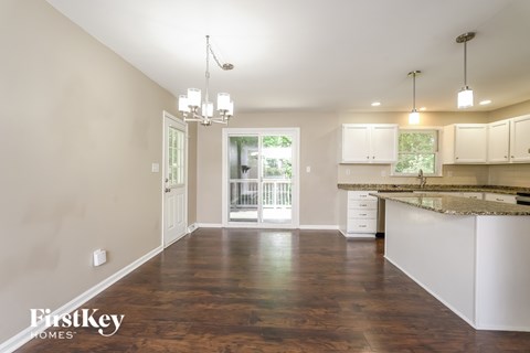 A spacious kitchen and living room with wooden floors and white cabinetry.