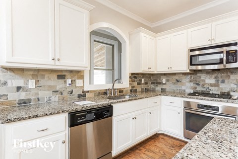 A kitchen with white cabinets and granite countertops.