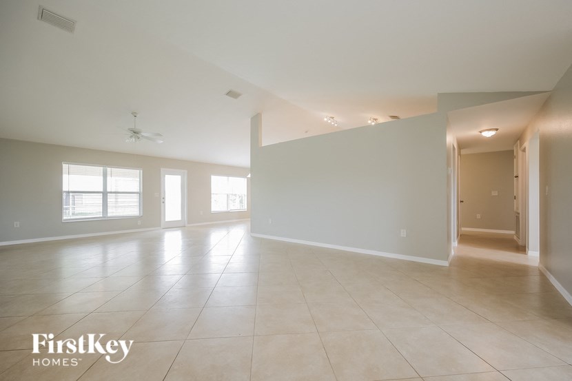an empty living room with white walls and tile floors