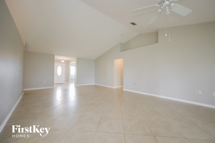 an empty living room with white walls and a ceiling fan
