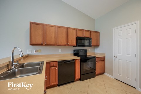 a kitchen with wood cabinets and black appliances and a sink