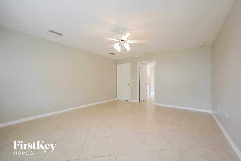 a spacious living room with white tile flooring and a ceiling fan