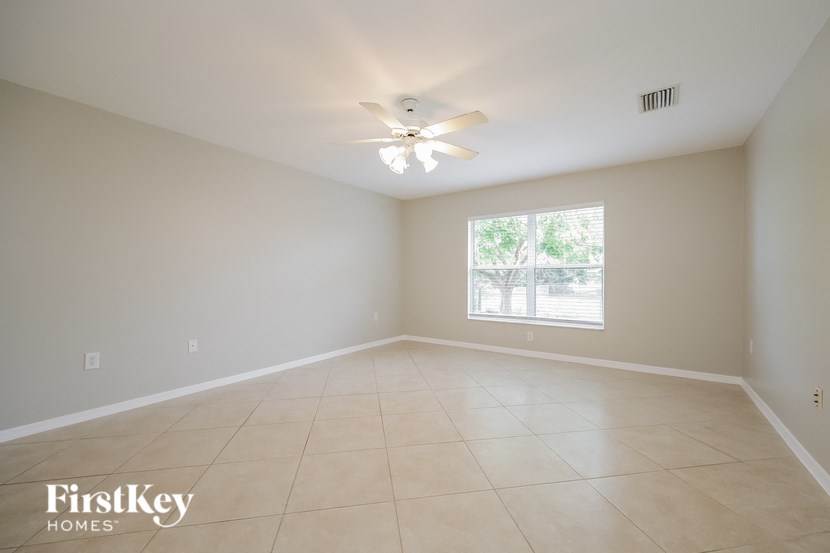 an empty living room with a ceiling fan and a window