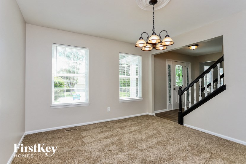 A well-lit room with a carpeted floor and a staircase.