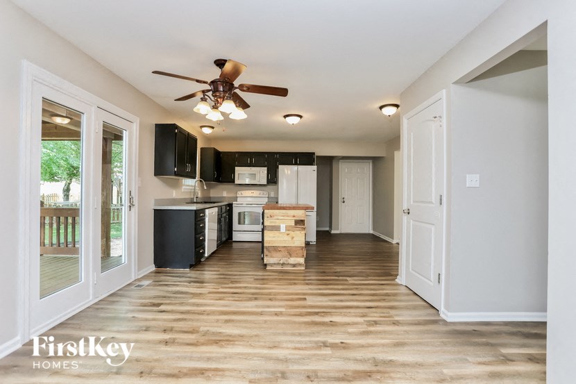 A kitchen with a fan on the ceiling and wooden floors.