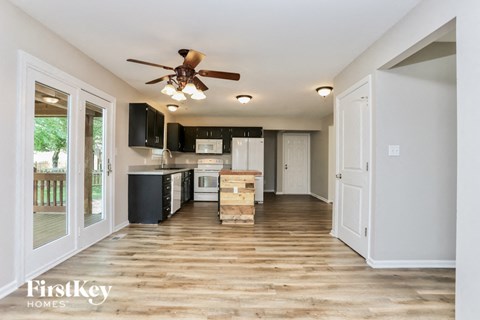 A kitchen with a fan on the ceiling and wooden floors.