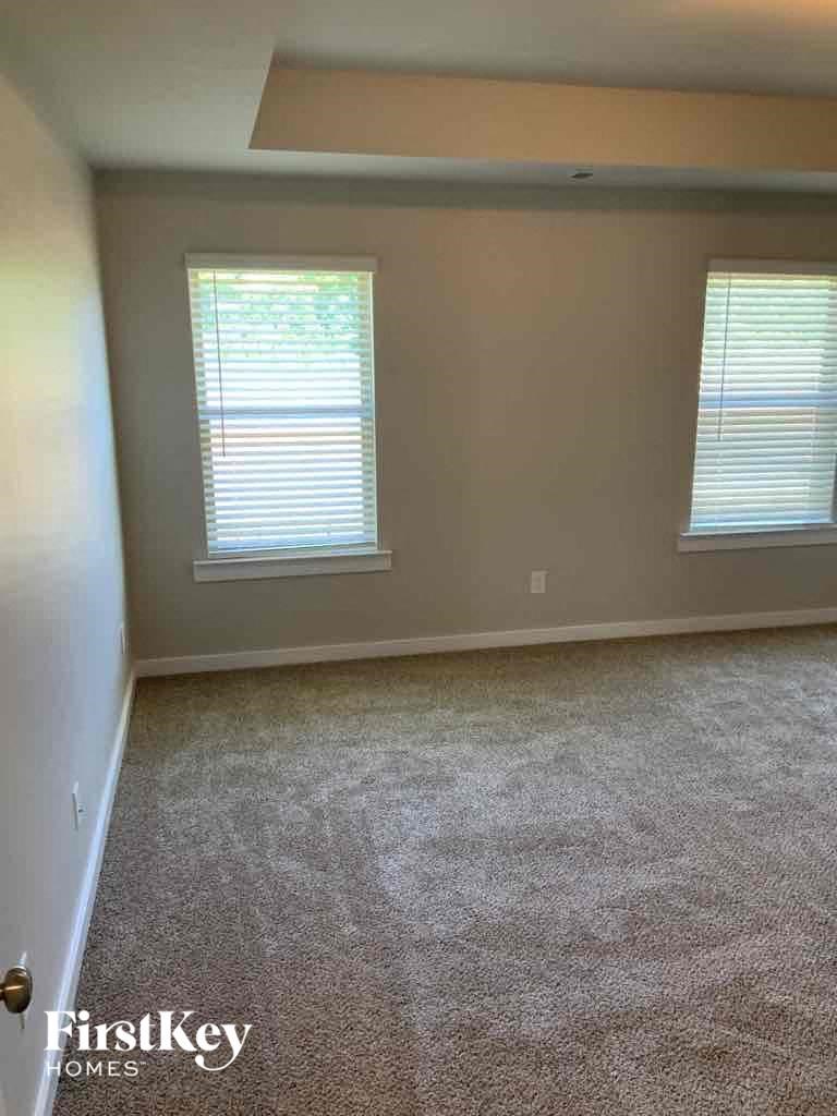 an empty room with carpet and two windows