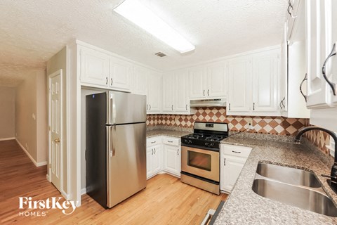 A kitchen with a stainless steel refrigerator and a stove top oven.