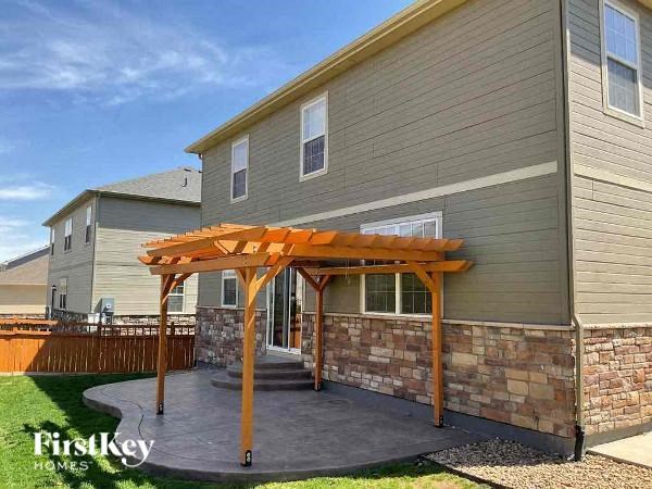 a backyard patio with a wooden structure in front of a house