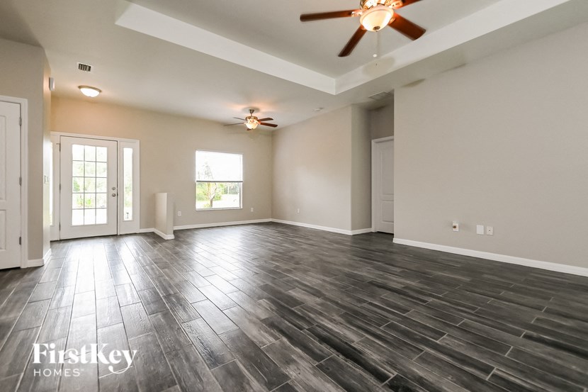 an empty living room with wood floors and a ceiling fan