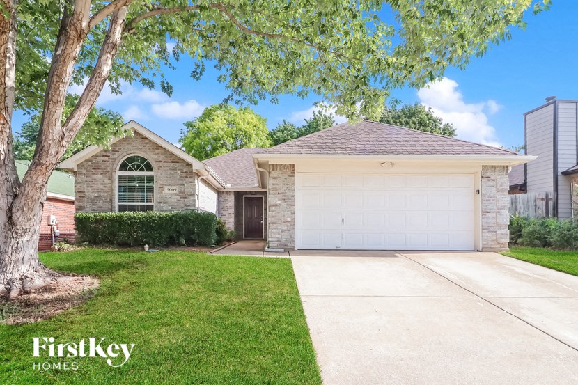 a home with a white garage door and a tree