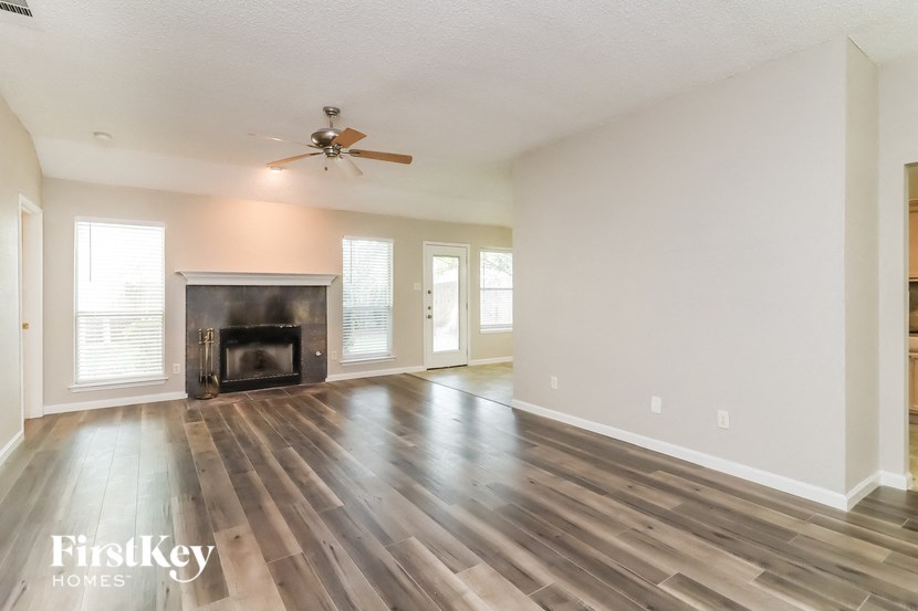 a empty living room with a fireplace and a ceiling fan