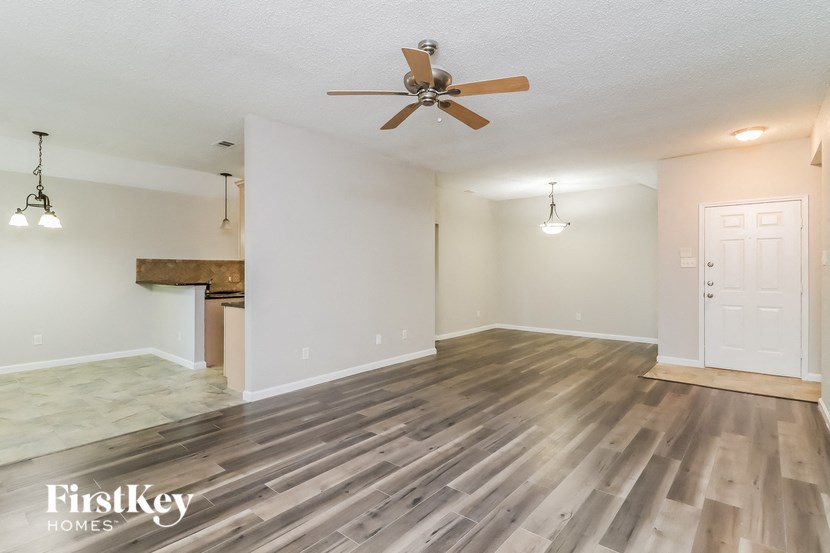 the living room with wood flooring and a ceiling fan