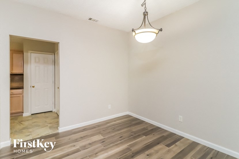 an empty living room with wood flooring and a chandelier