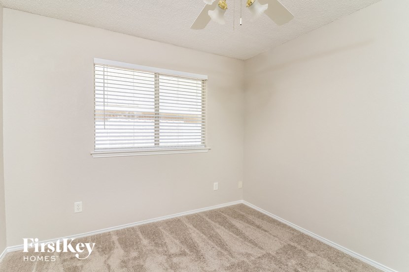 an empty room with a window and a ceiling fan