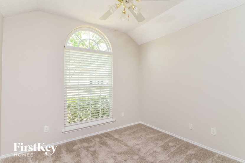 an empty bedroom with a large window and a ceiling fan
