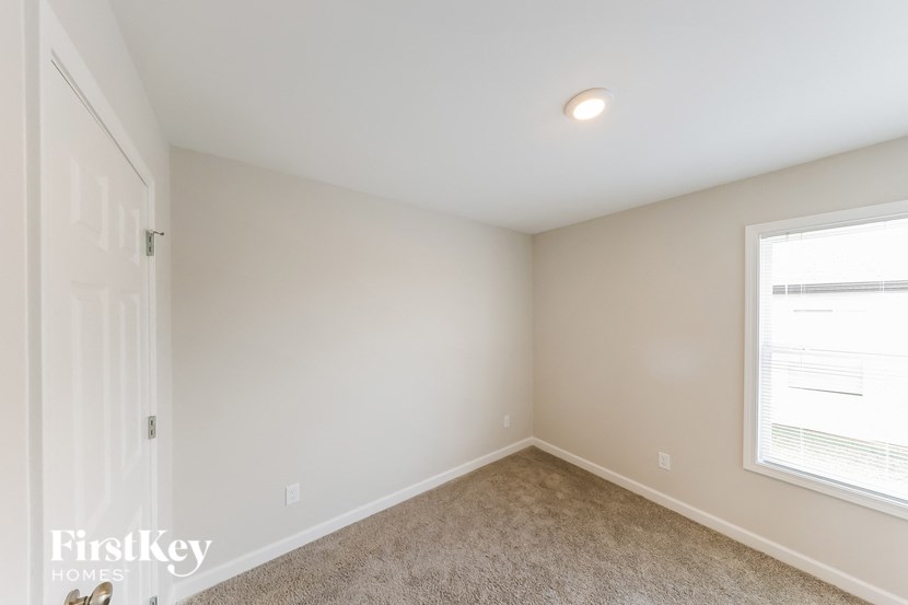 a bedroom with white walls and a window and carpet