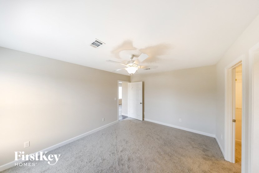 an empty living room with a ceiling fan and white walls