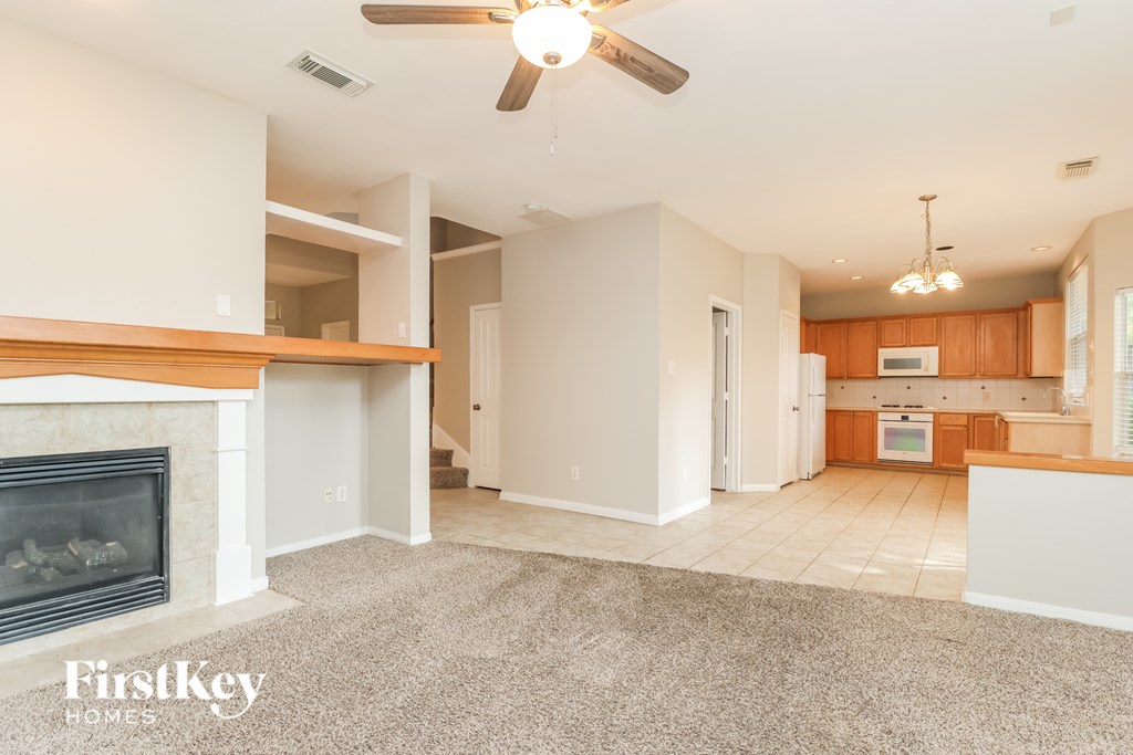 A spacious living room with a fireplace and a ceiling fan.