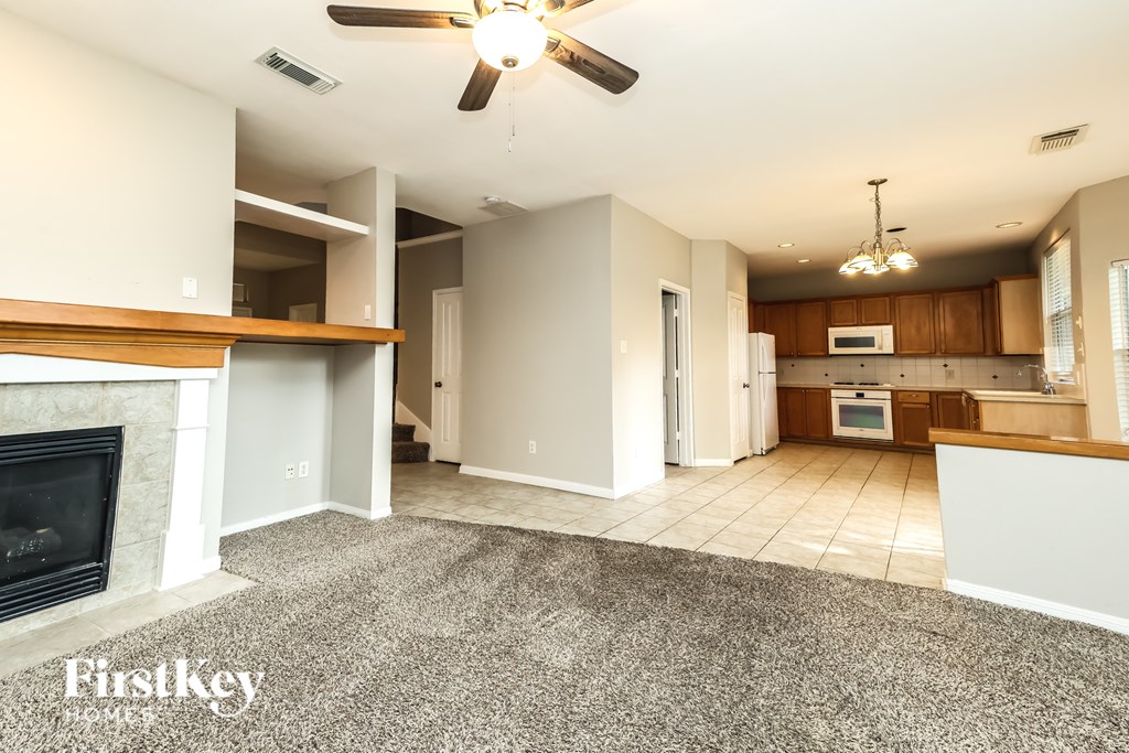 A spacious living room with a fireplace and a ceiling fan.