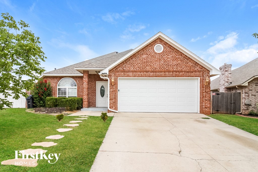 a brick house with a white garage door and a lawn