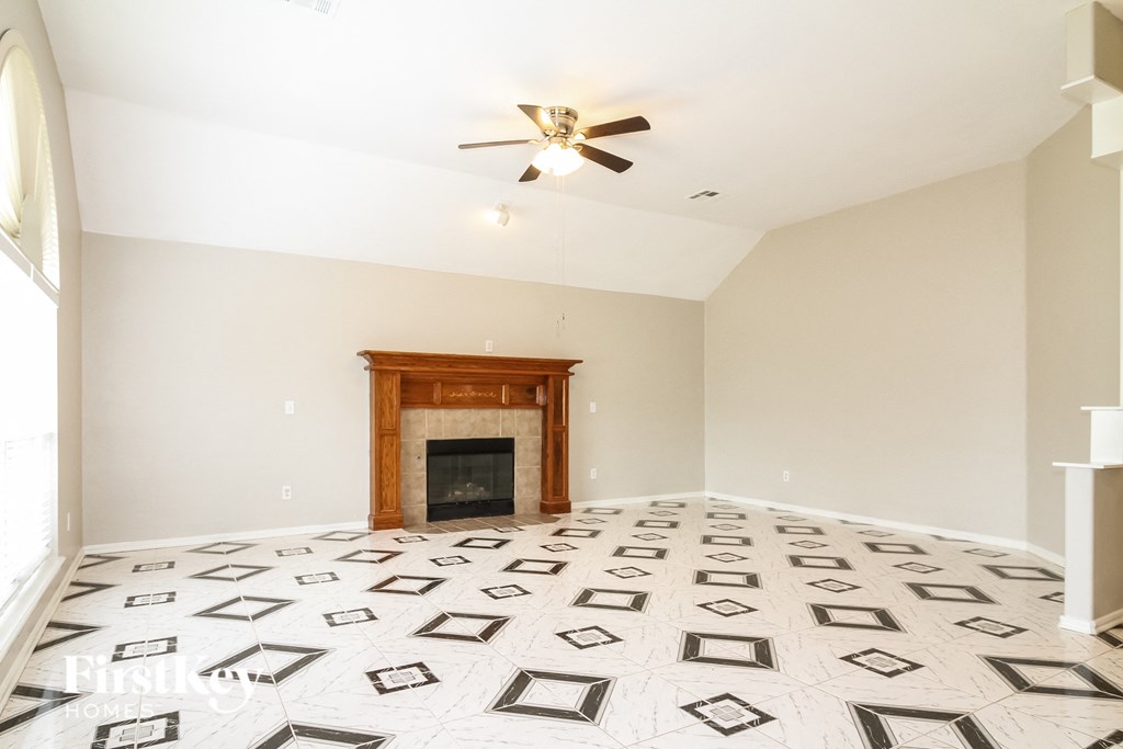 an empty living room with a fireplace and a ceiling fan