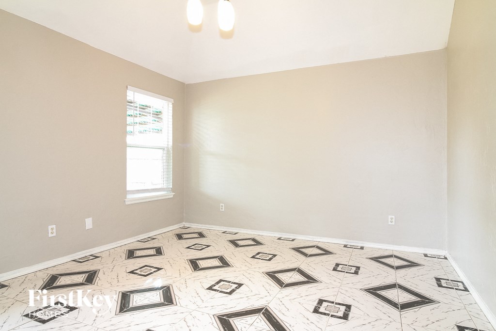 an empty room with white and black tiled floor and a window