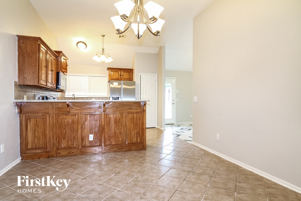 an empty kitchen with wooden cabinets and a tile floor