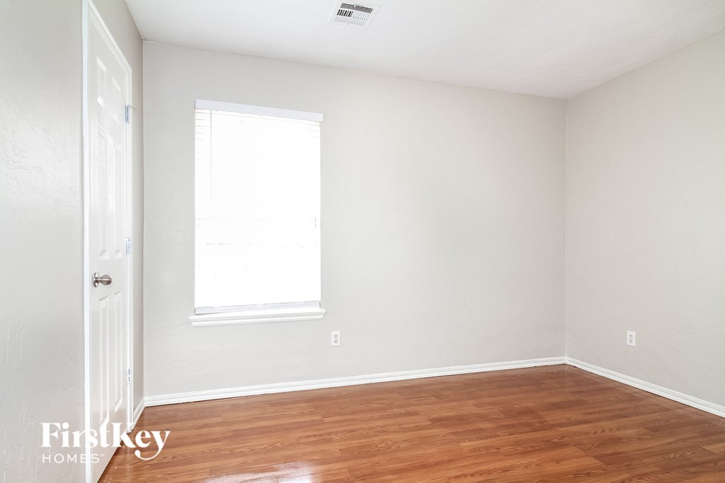 a bedroom with wood floors and white walls and a window
