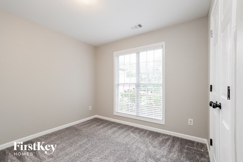 a bedroom with a large window and a carpeted floor