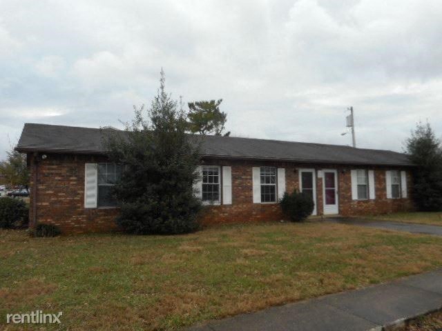 A small brick building with a black roof and a white door.