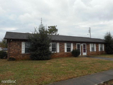 A small brick building with a black roof and a white door.