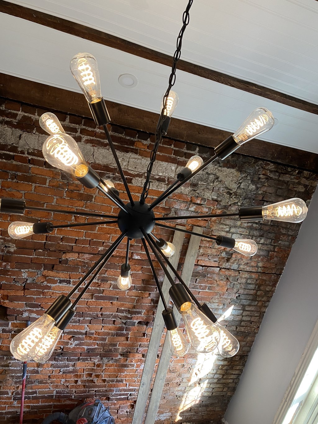 a chandelier with bulbs hanging from a brick wall
