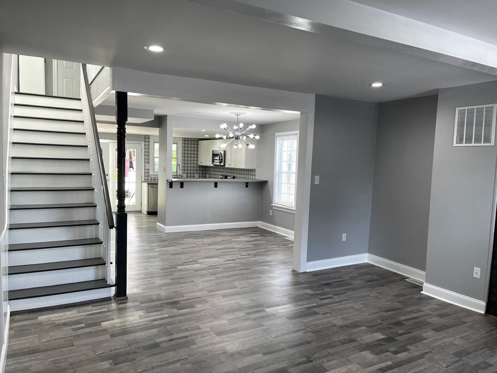 a renovated living room with a staircase and a kitchen