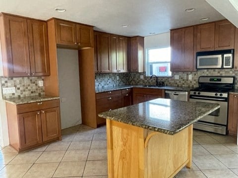 A kitchen with wooden cabinets and a granite countertop.
