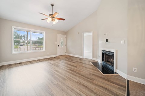 A spacious living room with a fireplace and a ceiling fan.