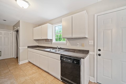 A kitchen with white cabinets and a black dishwasher.
