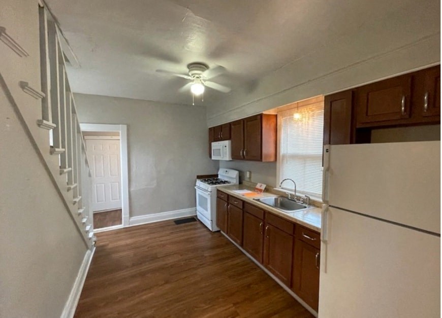 an empty kitchen with wood flooring and white appliances