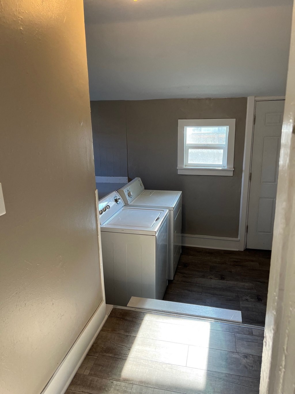 an empty laundry room with three washes and a window