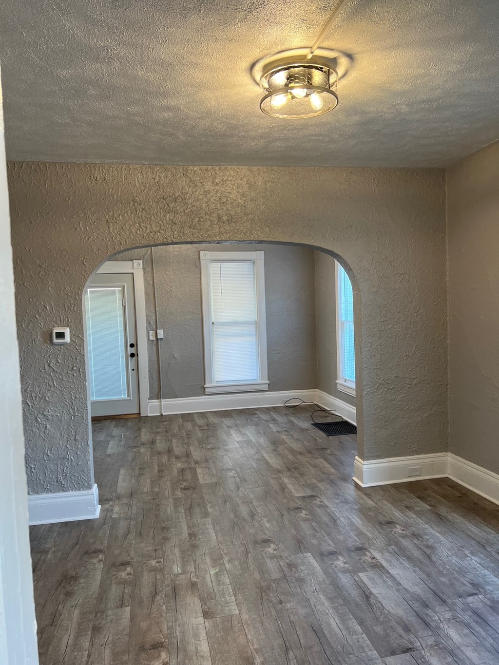 an empty living room with wood floors and an arched doorway