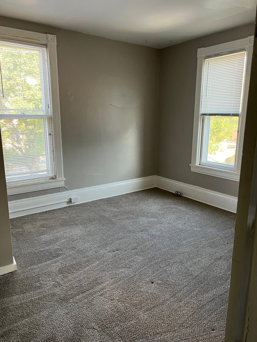 an empty room with two windows and a carpet